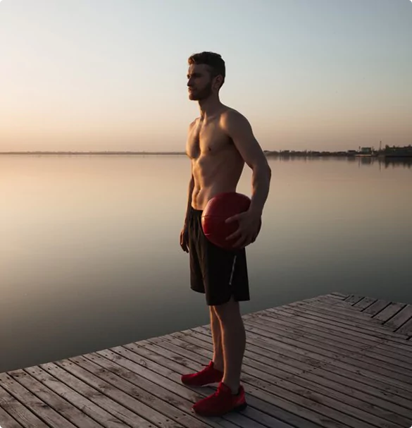 A man performs an exercise on a mat, focusing on his form and technique in a well-lit environment.