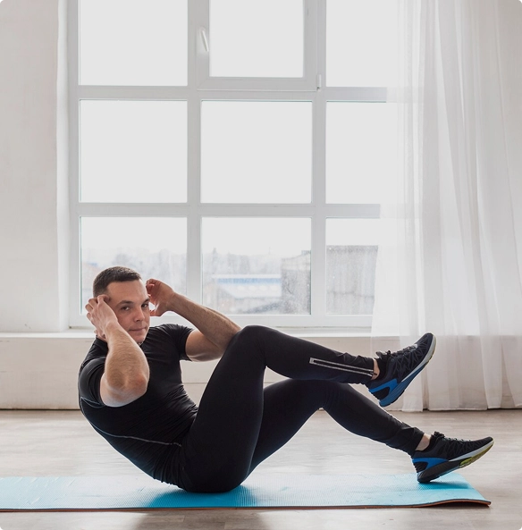 A man performs an exercise on a mat, focusing on his form and technique in a well-lit environment.