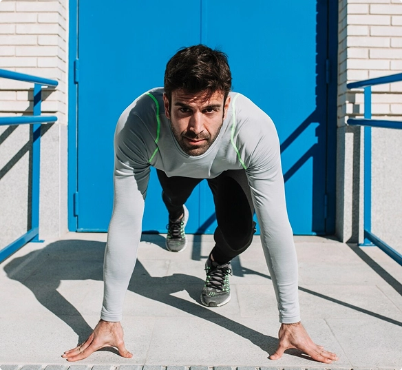 A man performs an exercise on a mat, focusing on his form and technique in a well-lit environment.