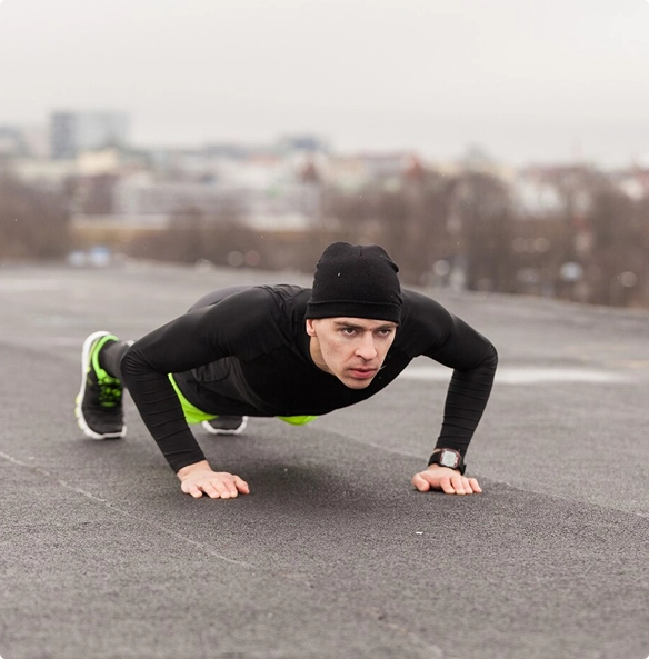A man is engaged in push-ups on the sidewalk, demonstrating physical exercise in a bustling street setting.