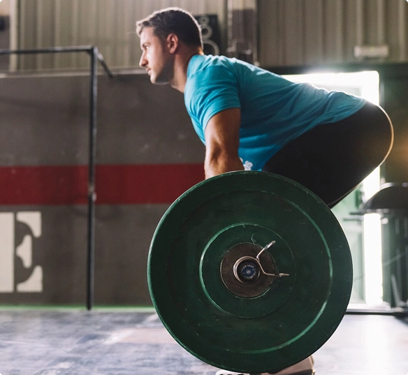 A man performs a squat with a barbell, demonstrating strength training in a fitness environment.