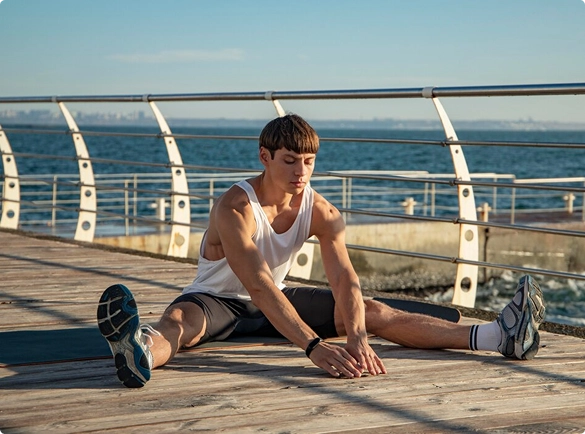 A man on the ground performing stretches, focusing on flexibility and fitness.