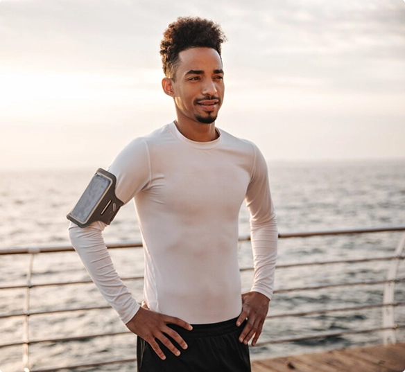 A man in a white shirt stands on a wooden dock, with the water and horizon visible in the background.