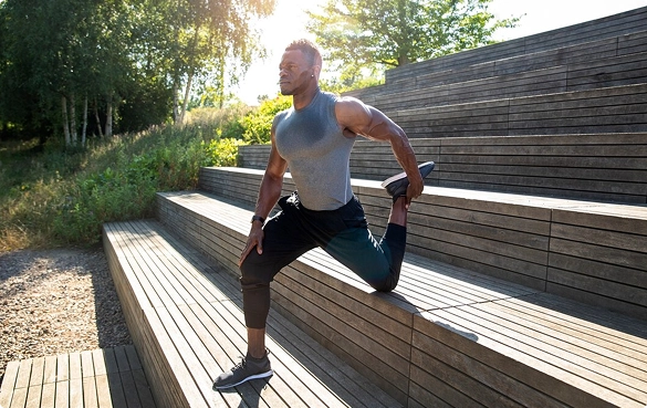A man in a white shirt stands on a wooden dock, with the water and horizon visible in the background.