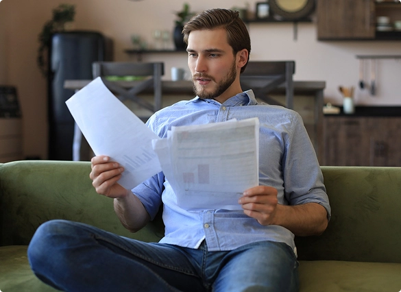  A man comfortably seated on a couch, reviewing important documents.